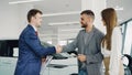 Handsome male car buyer is getting key fob from friendly salesman and shaking hands with him while standing beside auto Royalty Free Stock Photo