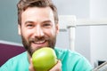 Handsome male doctor with beard smiling and holding green apple Royalty Free Stock Photo