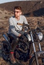 Handsome male in eyeglasses motorcyclist travels on motorbike, has adventure trip, likes active and admiring place.