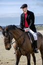 Handsome Male Horse Rider riding horse on beach in traditional clothing Royalty Free Stock Photo