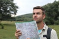 Handsome male looking at map and planning trip after getting lost alone in the woods