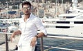 Handsome male model posing in front of a luxury yacht