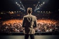 Handsome male motivational speaker holding a microphone in front on an audience. Man in a spotlight talking to a crowd