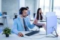 Handsome male operator with headset in blue suit working on computer in call center. Royalty Free Stock Photo