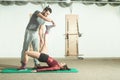 Handsome male personal trainer with a beard helping young fitness girl to stretch her muscles after hard training workout, selecti Royalty Free Stock Photo