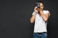 Handsome male photographer, a reporter with retro camera preparing to take a photo, isolated at the dark background Royalty Free Stock Photo