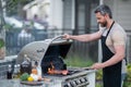 Handsome male preparing barbecue, grill outdoors. Man cooking meat and fish on barbecue in the backyard. Grill cook Royalty Free Stock Photo