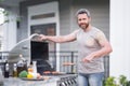 Handsome male preparing barbecue, grill outdoors. Man cooking meat and fish on barbecue in the backyard. Grill cook Royalty Free Stock Photo