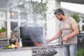 Handsome male preparing barbecue, grill outdoors. Man cooking meat and fish on barbecue in the backyard. Grill cook Royalty Free Stock Photo