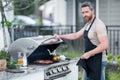 Handsome male preparing barbecue, grill outdoors. Man cooking meat and fish on barbecue in the backyard. Grill cook Royalty Free Stock Photo