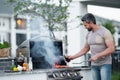 Handsome male preparing barbecue, grill outdoors. Man cooking meat and fish on barbecue in the backyard. Grill cook Royalty Free Stock Photo