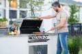 Handsome male preparing barbecue, grill outdoors. Man cooking meat and fish on barbecue in the backyard. Grill cook Royalty Free Stock Photo