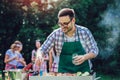 Man preparing barbecue outdoors for friends