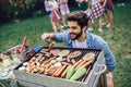 Male preparing barbecue outdoors for friends