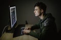 Handsome male programmer, IT person, hacker, works in computer on internet in dark room in front of pc