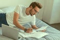 Handsome male student concentrating on printouts while doing homework