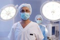 A handsome male surgeon with glasses is in a medical hospital room with a nurse standing behind him in very good