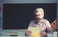 Handsome male teacher checking homework in classroom.