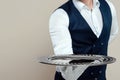 Handsome male waiter, white shirt, holds a silver tray, hand behind his back. Concept of wait staff serving customers in a Royalty Free Stock Photo