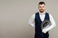 Handsome male waiter, white shirt, holds a silver tray, hand behind his back. Concept of wait staff serving customers in a Royalty Free Stock Photo