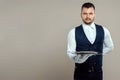 Handsome male waiter, white shirt, holds a silver tray, hand behind his back. Concept of wait staff serving customers in a Royalty Free Stock Photo