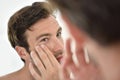 Handsome man applying facial cream