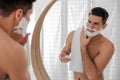 Handsome man applying shaving foam near mirror in bathroom Royalty Free Stock Photo