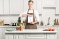 handsome man in apron showing tablet with loaded instagram page