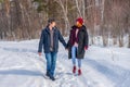 Handsome man and attractive young woman walking along snowy country road in sunny day. Beautiful look, male and female fashion,