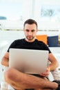 Handsome man on the beach typing on his laptop while sitting on his deck chair on summer resort Royalty Free Stock Photo