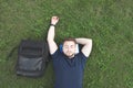 Handsome man with a beard and a backpack lays on the grass with his eyes closed Royalty Free Stock Photo