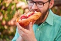 Goodly boy with a glasess tasting delicious food in the park. Nature background.