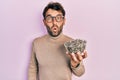 Handsome man with beard football reporter holding pumpkin seeds bowl scared and amazed with open mouth for surprise, disbelief Royalty Free Stock Photo