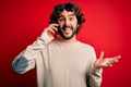 Handsome man with beard having conversation talking on the smartphone over red background very happy and excited, winner Royalty Free Stock Photo