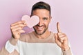 Handsome man with beard holding heart shape paper smiling with an idea or question pointing finger with happy face, number one Royalty Free Stock Photo