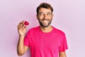 Handsome man with beard holding pink geode precious gemstone looking positive and happy standing and smiling with a confident