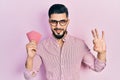 Handsome man with beard holding poker cards doing ok sign with fingers, smiling friendly gesturing excellent symbol