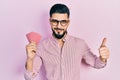 Handsome man with beard holding poker cards smiling happy and positive, thumb up doing excellent and approval sign