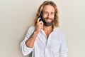 Handsome man with beard and long hair having conversation talking on the smartphone looking positive and happy standing and Royalty Free Stock Photo