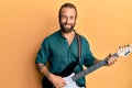 Handsome man with beard and long hair playing electric guitar smiling with a happy and cool smile on face Royalty Free Stock Photo