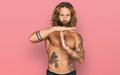 Handsome man with beard and long hair standing shirtless showing tattoos doing time out gesture with hands, frustrated and serious