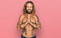 Handsome man with beard and long hair standing shirtless showing tattoos praying with hands together asking for forgiveness Royalty Free Stock Photo