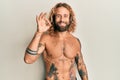 Handsome man with beard and long hair standing shirtless showing tattoos smiling positive doing ok sign with hand and fingers