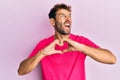 Handsome man with beard making heart symbol with hands shape angry and mad screaming frustrated and furious, shouting with anger