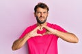 Handsome man with beard making heart symbol with hands shape skeptic and nervous, frowning upset because of problem Royalty Free Stock Photo