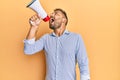 Handsome man with beard shouting through megaphone angry and mad screaming frustrated and furious, shouting with anger looking up