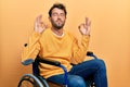 Handsome man with beard sitting on wheelchair relaxed and smiling with eyes closed doing meditation gesture with fingers Royalty Free Stock Photo