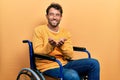 Handsome man with beard sitting on wheelchair smiling with hands palms together receiving or giving gesture Royalty Free Stock Photo