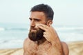 Handsome Man with beard, In Sunglasses Sunbathing With Sunscreen Lotion Body In Summer. Male Fitness Model Tanning Using Solar Blo