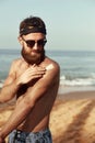 Handsome Man with beard, In Sunglasses Sunbathing With Sunscreen Lotion Body In Summer. Male Fitness Model Tanning Using Solar Blo Royalty Free Stock Photo